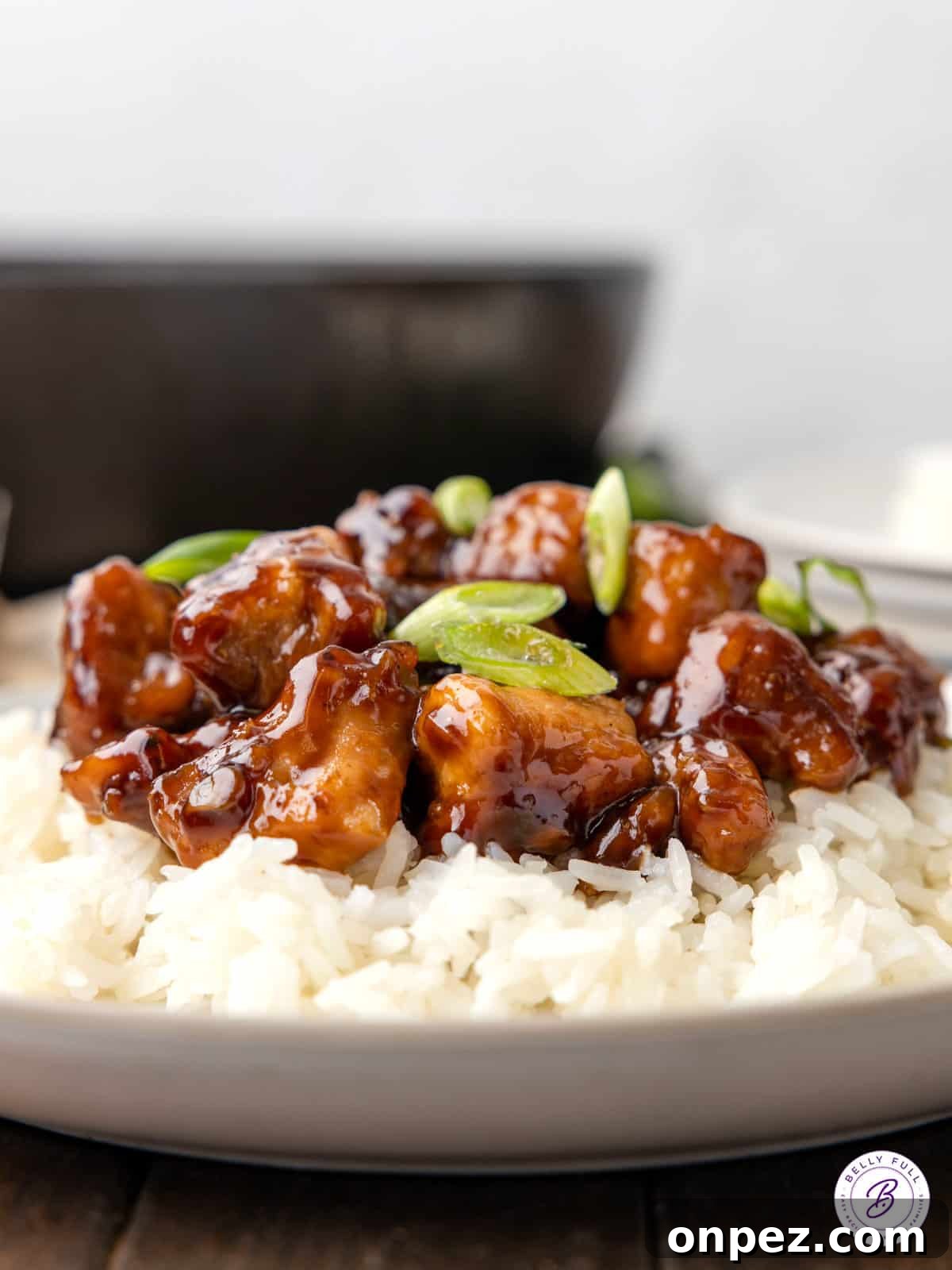 Featuring tender, juicy pieces of chicken in a sticky-sweet sauce, this Easy Bourbon Chicken tastes better than takeout! Side view of a plate of bourbon chicken on white rice