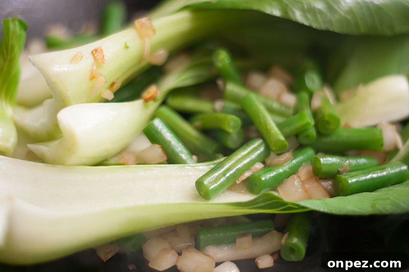 Stir fried pak choi and beans in a wok