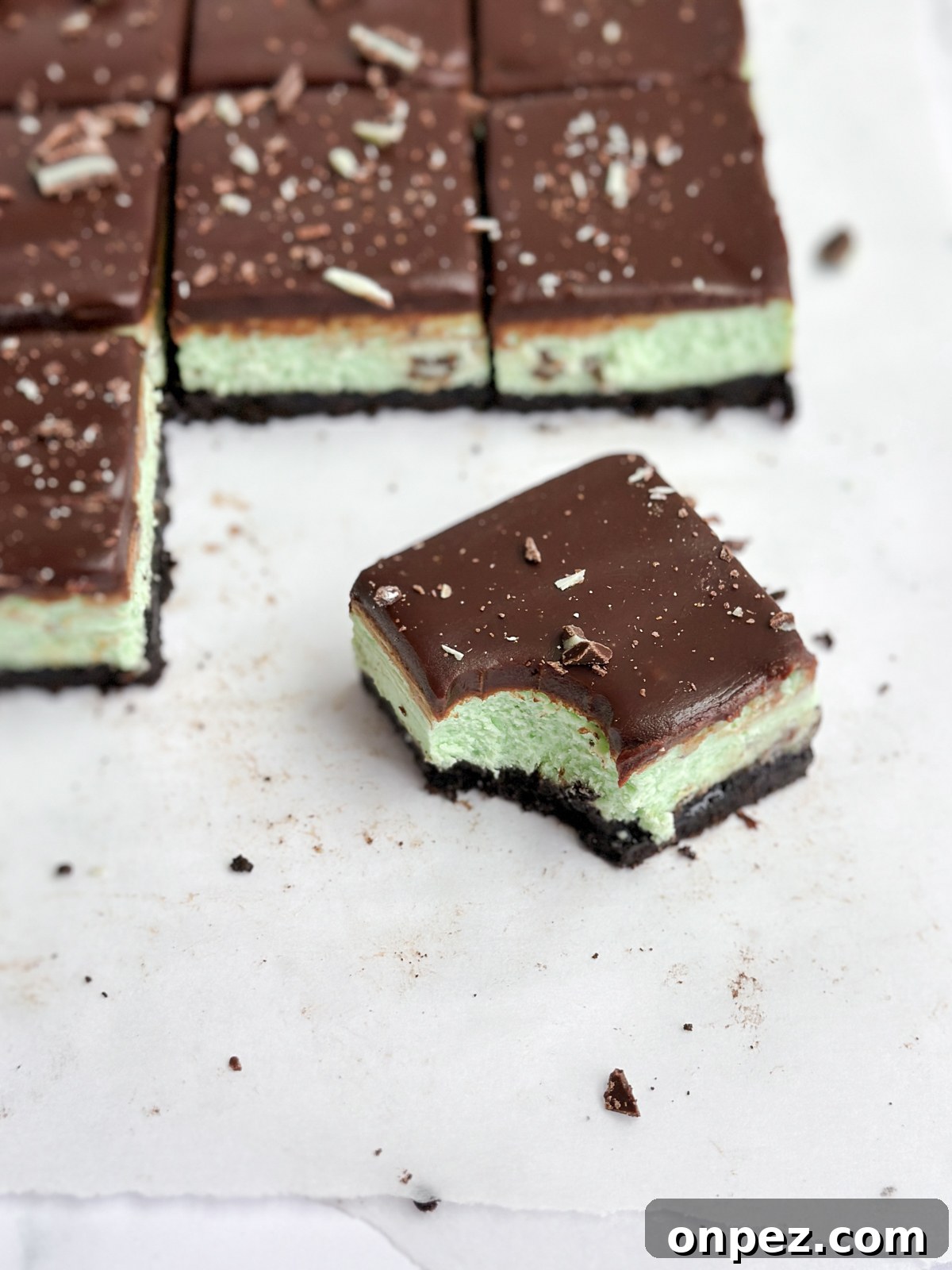 Decadent Chocolate Mint Cheesecake Bars 14 a single square of chocolate mint cheesecake with a bite taken out.