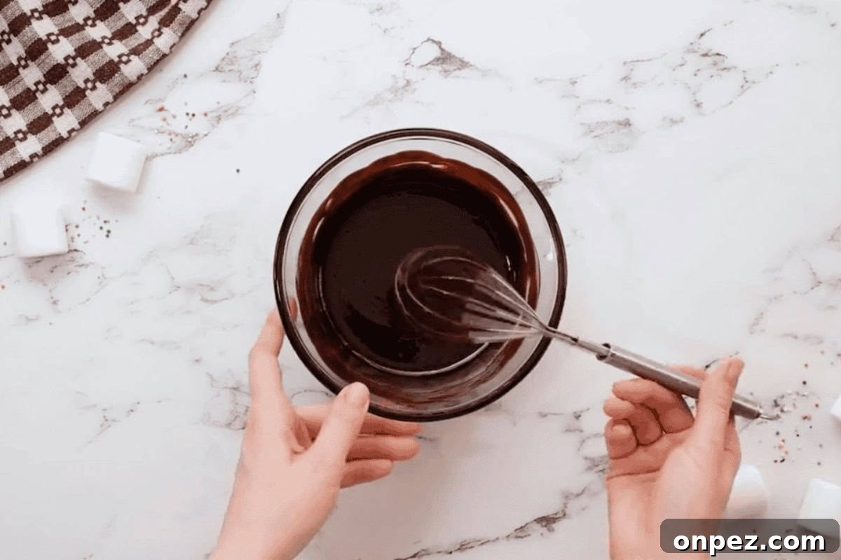 Hot Cocoa Cookies Recipe: Rich Chocolate Chip Cookies 4 melted chocolate and butter in a glass bowl with a whisk.