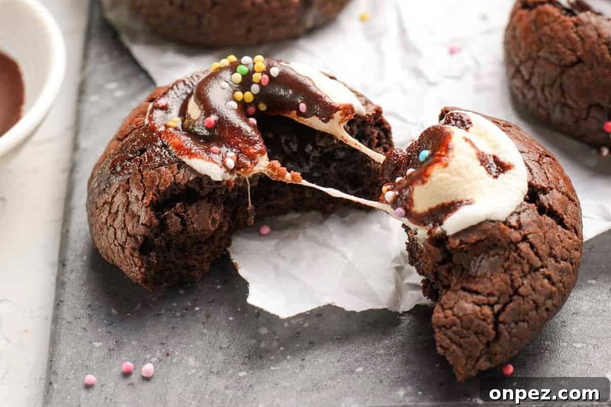 Hot Cocoa Cookies Recipe: Rich Chocolate Chip Cookies 3 a halved hot chocolate cookie featuring a marshmallow pull between the two halves.