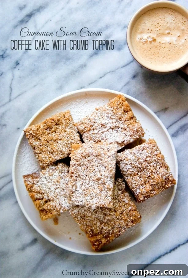 Cinnamon Sour Cream Coffee Cake with Crumb Topping Overhead shot of crumb coffee cake on plate with coffee in cup next to it.