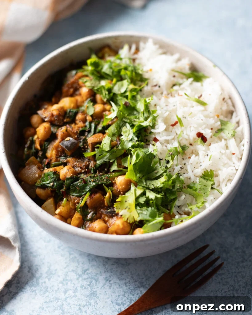 Chickpea, Eggplant and Potato Curry with Spinach Recipe 3 close up view of vegan chickpea curry with eggplant, potato and spinach served with rice and cilantro.