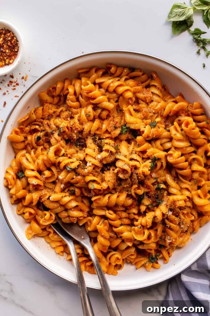 20-Minute Creamy Vegan Tomato Pasta 5 A white ceramic pan wit pasta in an orange creamy sauce.