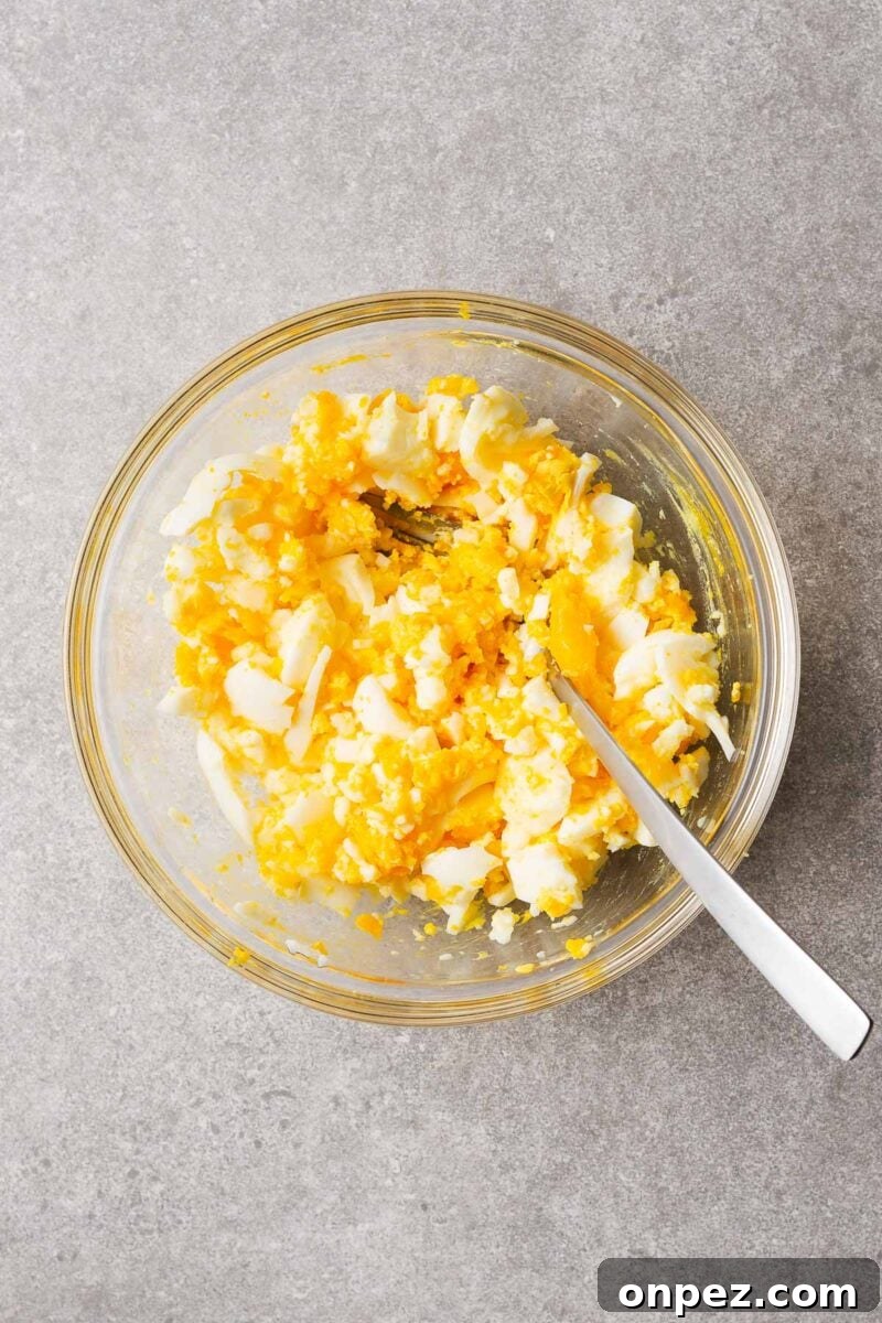 Boiled eggs squashed with a fork ready to make egg salad.