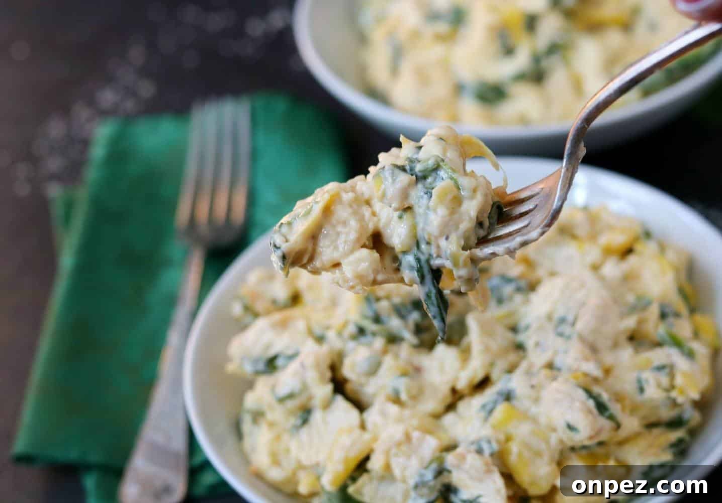 Instant Pot Spinach and Artichoke Chicken 3 Instant Pot chicken with spinach, cheese, and artichokes held on a fork above bowl