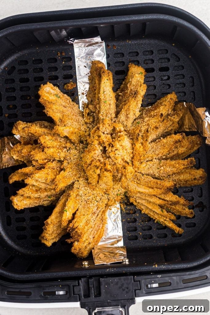 Golden crispy bloomed onion in the air fryer basket after being cooked