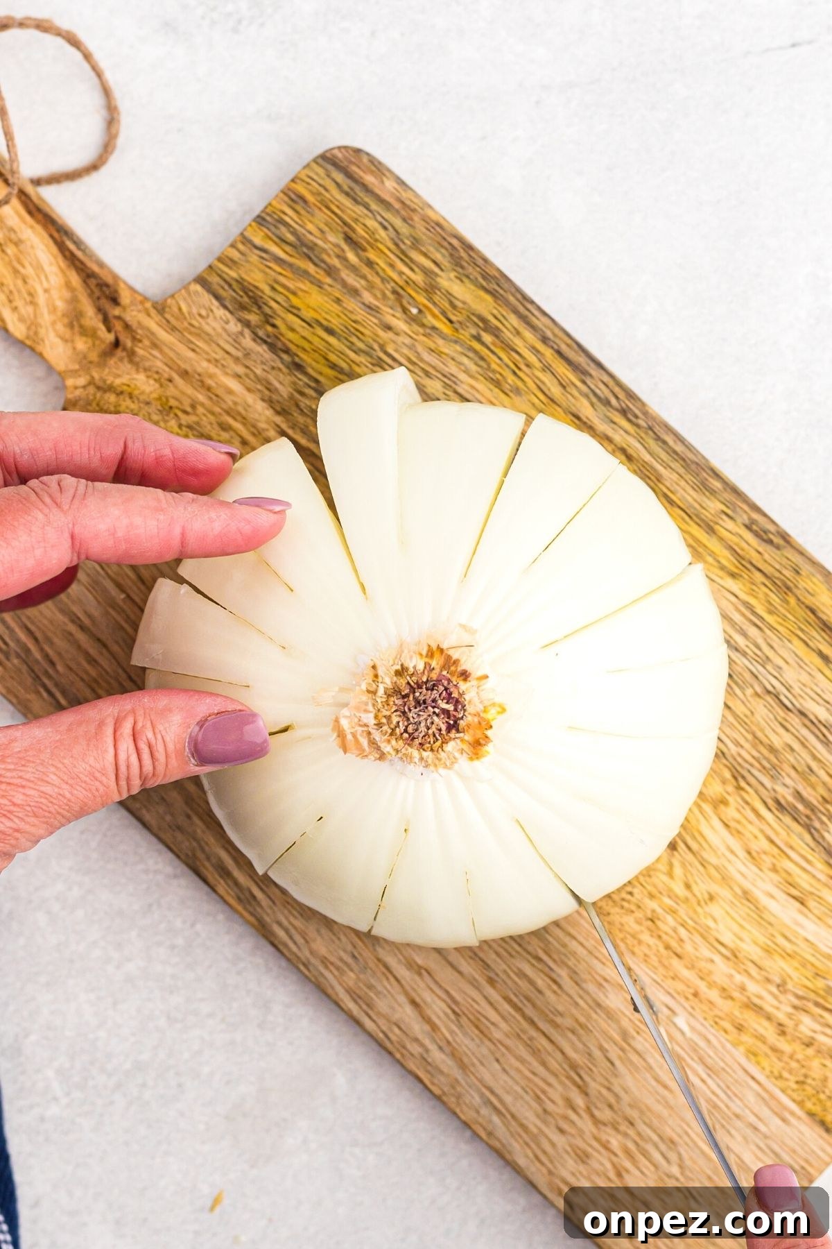 Sliced onion on a wooden cutting board with petals