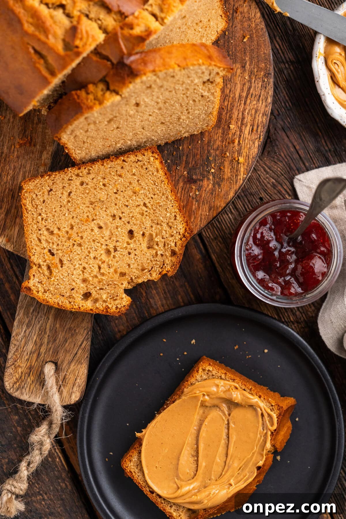 Slices of Peanut Butter Bread on a wooden board with another slice topped with peanut butter