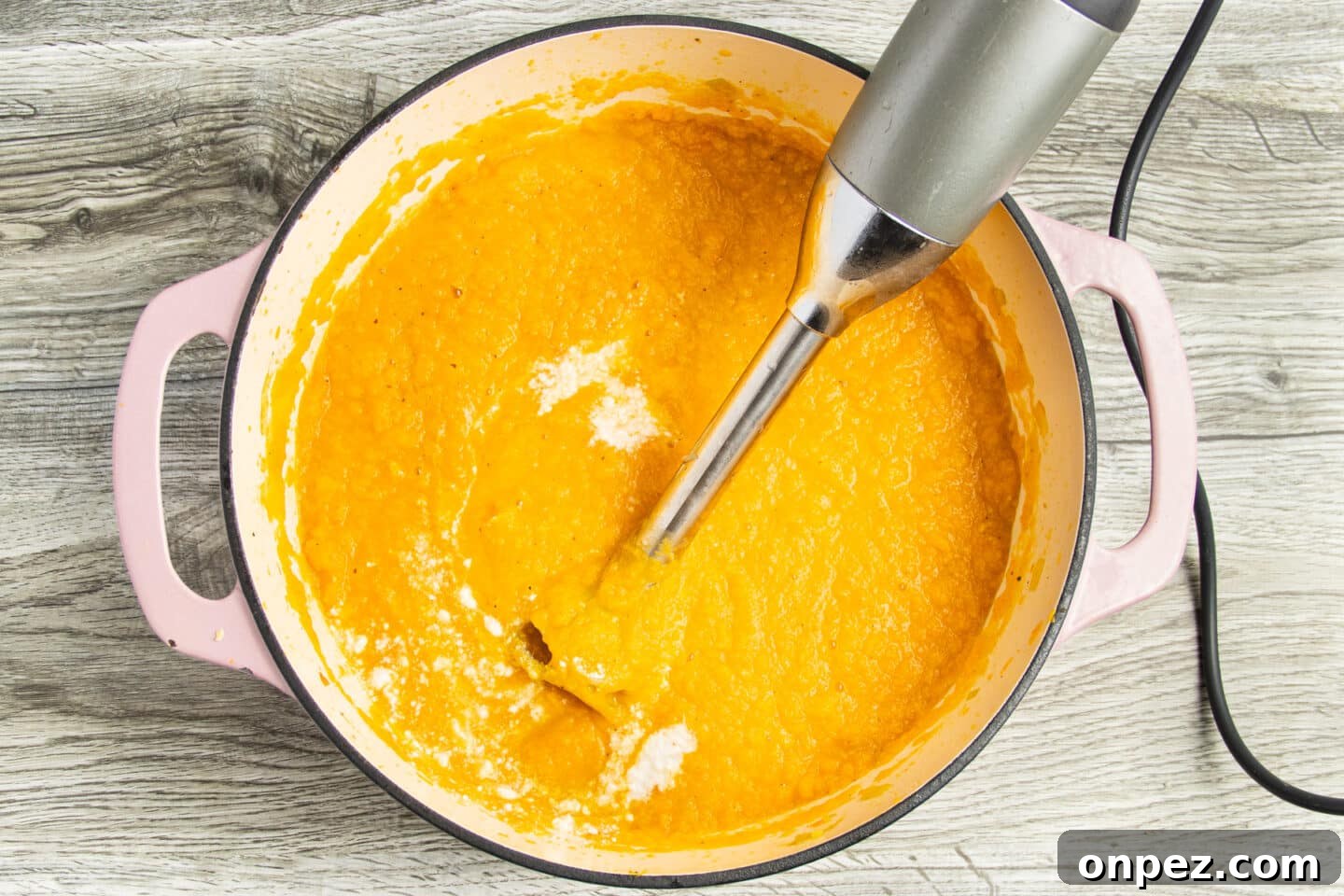 Roasted Carrot and Cauliflower Soup Recipe 7 Soup being blended with an immersion blender.