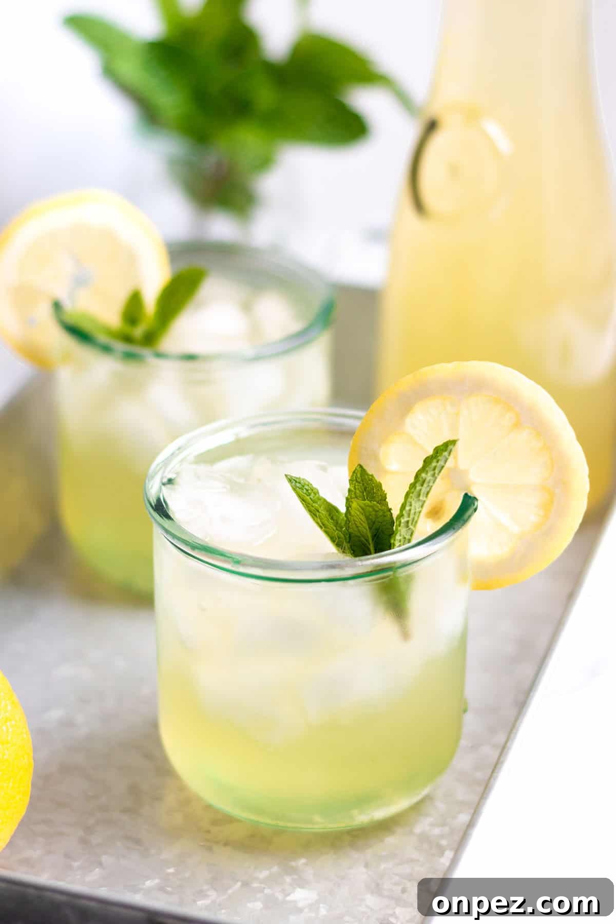 Two glasses with ice and lemonade with fresh mint and lemon slices.