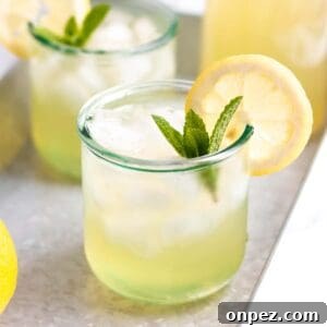 A glass of lemonade with a fresh lemon and mint.