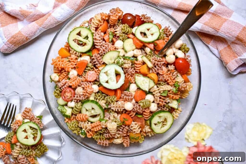 A bowl of pasta salad with faces carved into veggies.
