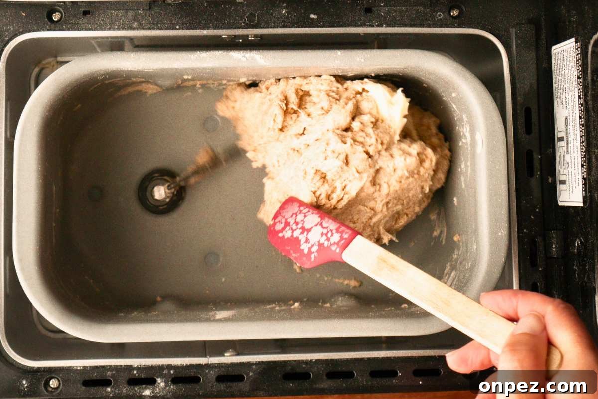 Honey Wheat Bread Recipe for Bread Machines 4 dough mixing in machine and water added with spatula.
